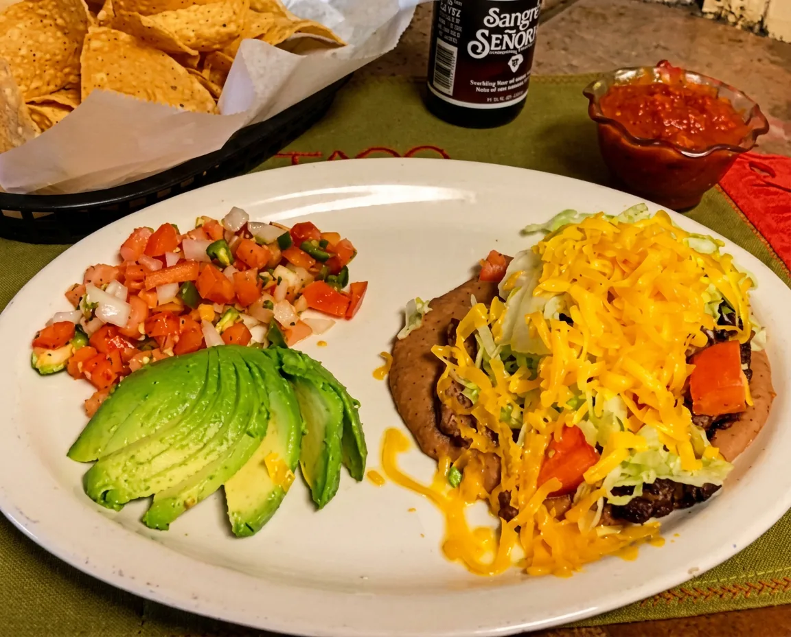 A chalupa plate with avocado, pico de gallo and melted cheese on a table at Taco El Conquistador